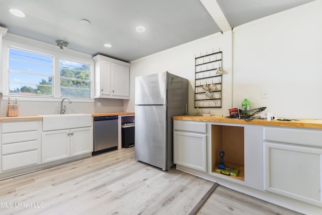 kitchen featuring wooden counters, stainless steel appliances, white cabinets, and sink