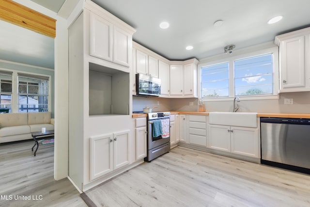 kitchen with white cabinets, light hardwood / wood-style floors, sink, and appliances with stainless steel finishes