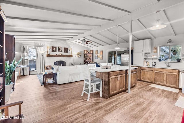 kitchen featuring a center island, ceiling fan, sink, decorative light fixtures, and vaulted ceiling with beams