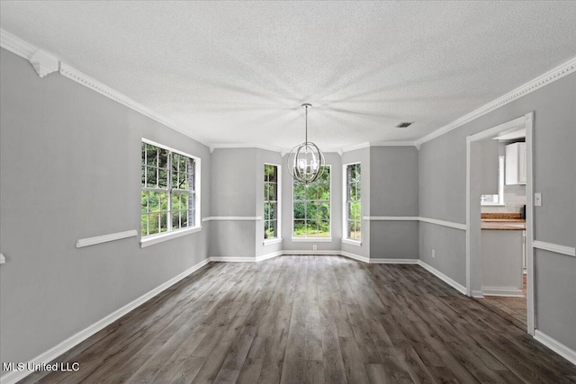 spare room with a healthy amount of sunlight, ornamental molding, dark wood-type flooring, and an inviting chandelier