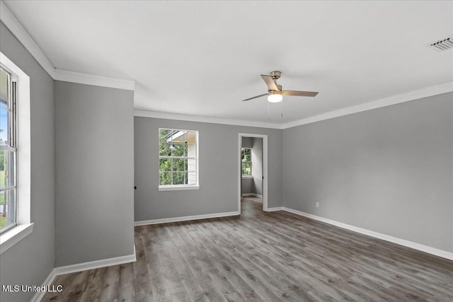 empty room with a wealth of natural light, crown molding, and hardwood / wood-style flooring