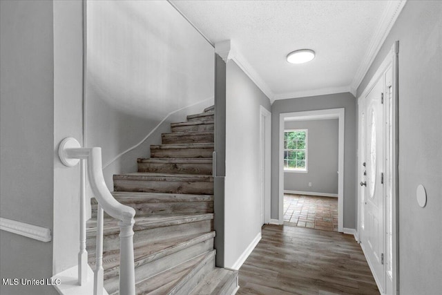 staircase featuring wood-type flooring, a textured ceiling, and crown molding