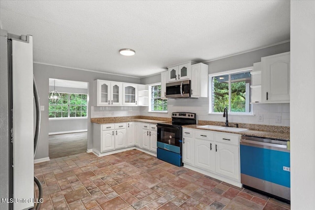 kitchen with sink, plenty of natural light, white cabinets, and appliances with stainless steel finishes