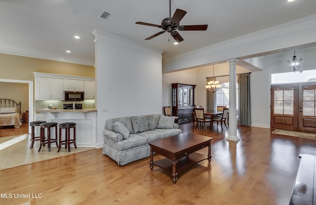 living room featuring light wood-style flooring, visible vents, french doors, decorative columns, and crown molding