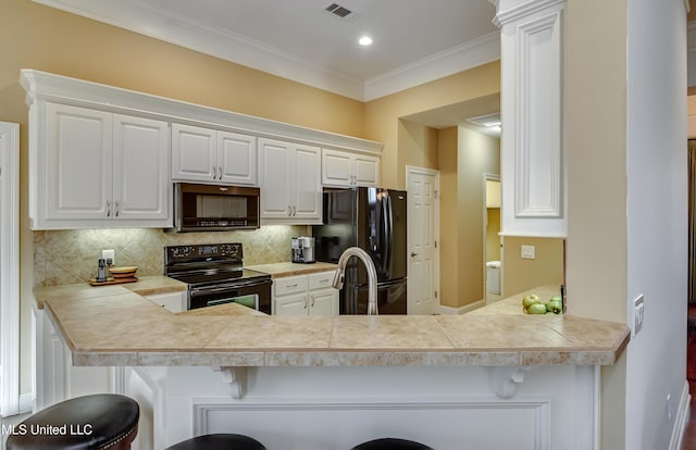 kitchen featuring white cabinets, black appliances, a peninsula, and a breakfast bar