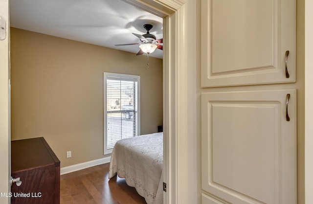 bedroom with a ceiling fan, baseboards, and dark wood-type flooring