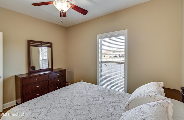 bedroom featuring multiple windows, ceiling fan, and baseboards