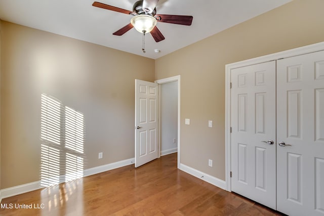 unfurnished bedroom featuring a ceiling fan, a closet, baseboards, and light wood finished floors