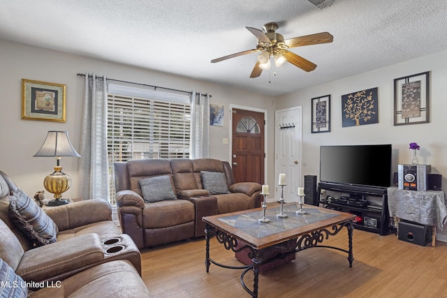 living room with ceiling fan, light hardwood / wood-style flooring, and a textured ceiling