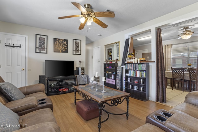 living room with ceiling fan, light hardwood / wood-style floors, and a textured ceiling