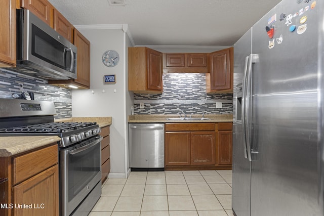 kitchen featuring appliances with stainless steel finishes, sink, ornamental molding, light tile patterned floors, and a textured ceiling