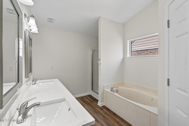 bathroom featuring wood finished floors, a stall shower, a jetted tub, and a sink