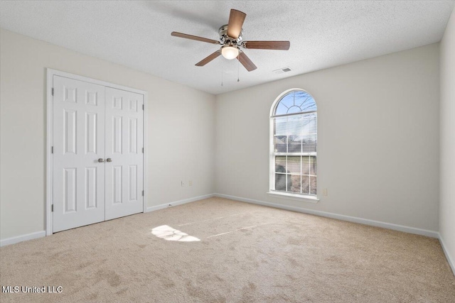 unfurnished bedroom with visible vents, carpet, a closet, and a textured ceiling