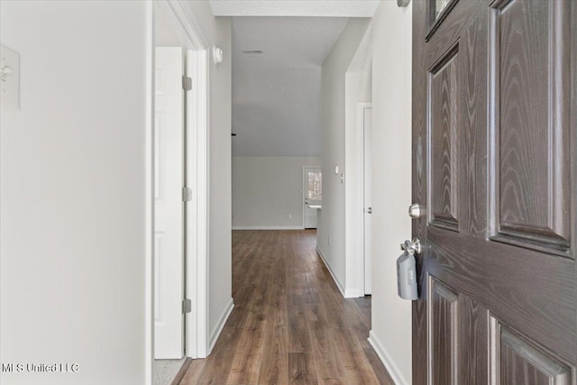 hall with baseboards, lofted ceiling, and wood finished floors