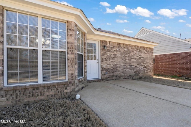 doorway to property with brick siding and a patio area