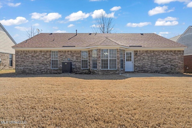 rear view of property featuring a yard, brick siding, and a shingled roof