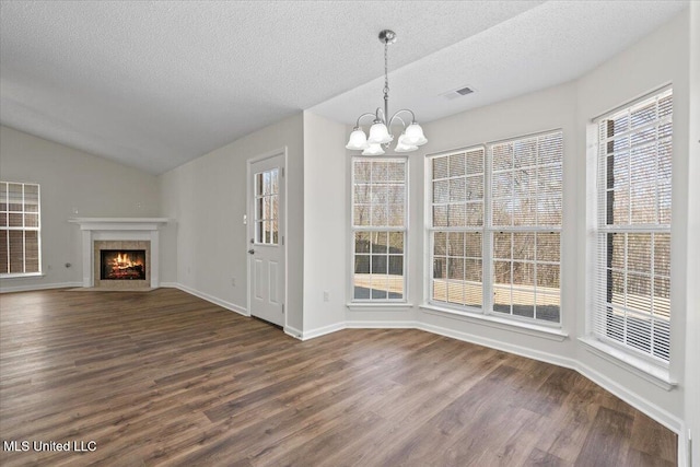 unfurnished dining area featuring a healthy amount of sunlight, visible vents, lofted ceiling, dark wood-type flooring, and a chandelier