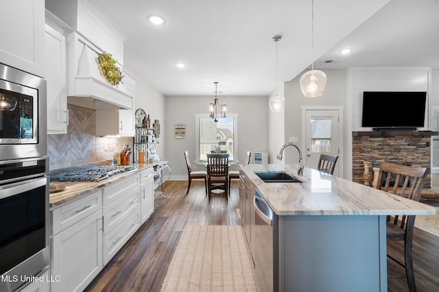 kitchen featuring a sink, appliances with stainless steel finishes, backsplash, a kitchen breakfast bar, and light stone countertops