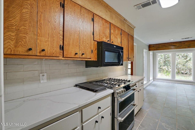 kitchen featuring light stone countertops, range with two ovens, and backsplash