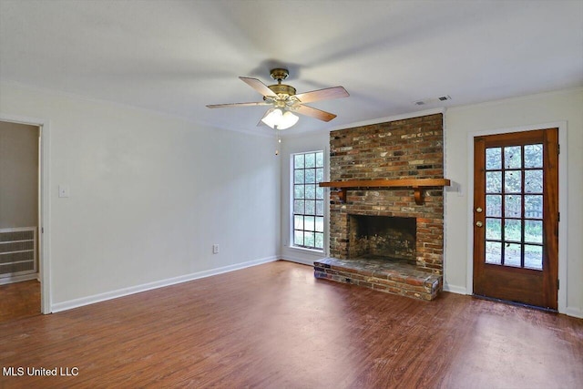 unfurnished living room with ceiling fan, crown molding, a brick fireplace, and dark hardwood / wood-style floors