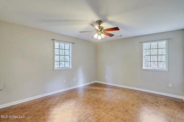 unfurnished room with light parquet flooring, ceiling fan, and a healthy amount of sunlight