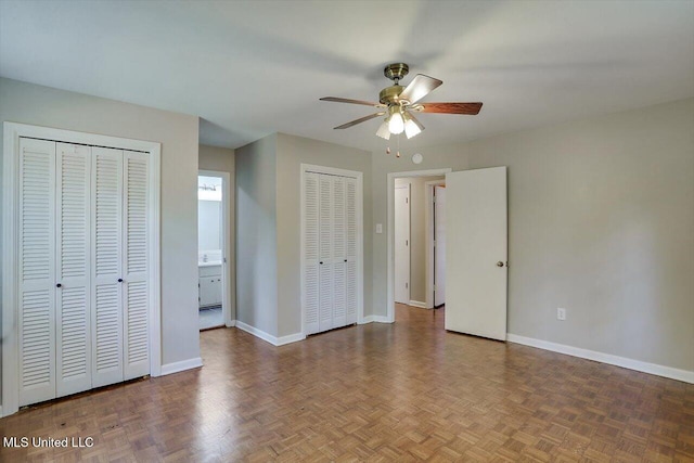 unfurnished bedroom featuring parquet flooring, ceiling fan, connected bathroom, and multiple closets