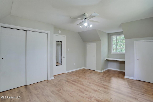 unfurnished bedroom featuring built in desk, ceiling fan, vaulted ceiling, and light hardwood / wood-style flooring