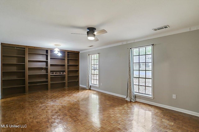 spare room featuring ornamental molding, dark parquet floors, plenty of natural light, and ceiling fan