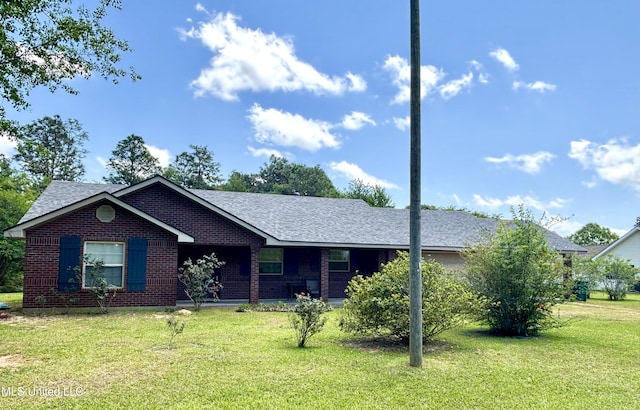 ranch-style home with brick siding, roof with shingles, a front yard, and covered porch