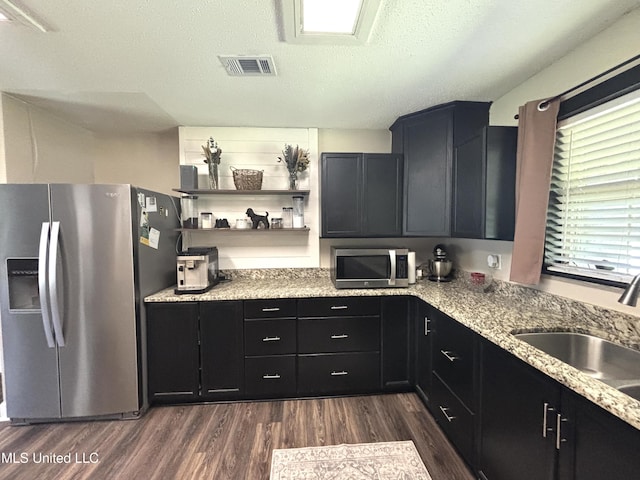 kitchen featuring a sink, dark cabinetry, appliances with stainless steel finishes, dark wood-type flooring, and visible vents