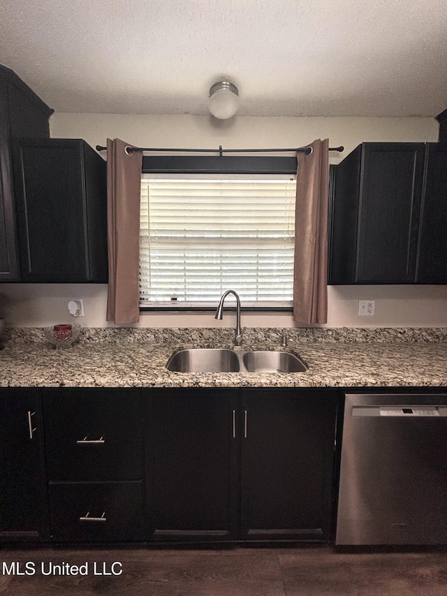 kitchen featuring dishwasher, dark cabinetry, and a sink