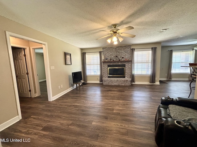 living area featuring a textured ceiling, dark wood-style floors, a ceiling fan, baseboards, and a brick fireplace