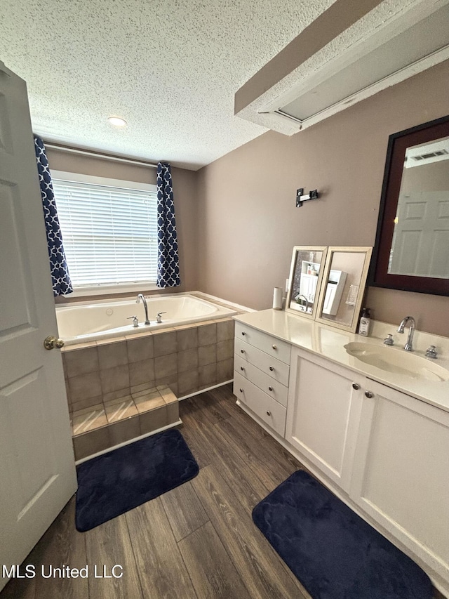 full bath featuring a bath, wood finished floors, a textured ceiling, and vanity
