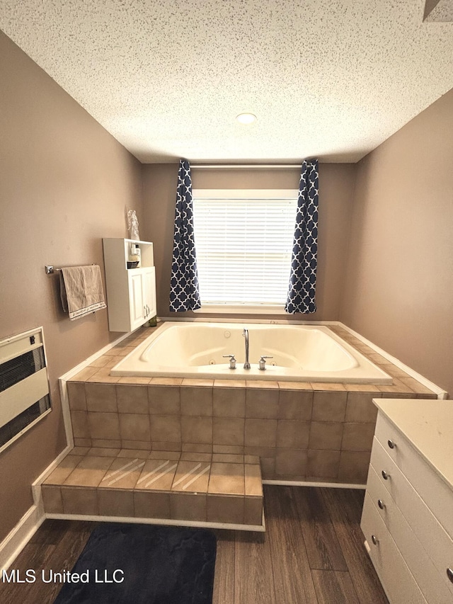 full bathroom featuring heating unit, wood finished floors, a textured ceiling, and a tub with jets