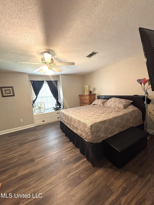 bedroom featuring dark wood finished floors, a ceiling fan, a textured ceiling, and visible vents