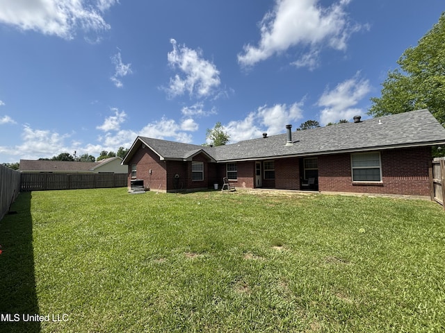 rear view of house featuring a fenced backyard, brick siding, and a yard