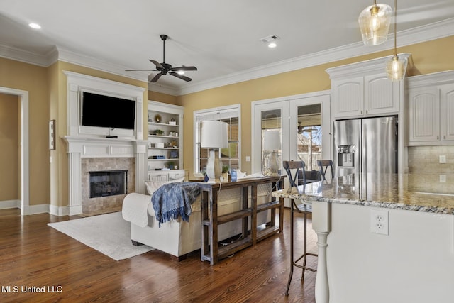 living area featuring dark wood-style floors, visible vents, a fireplace, and crown molding