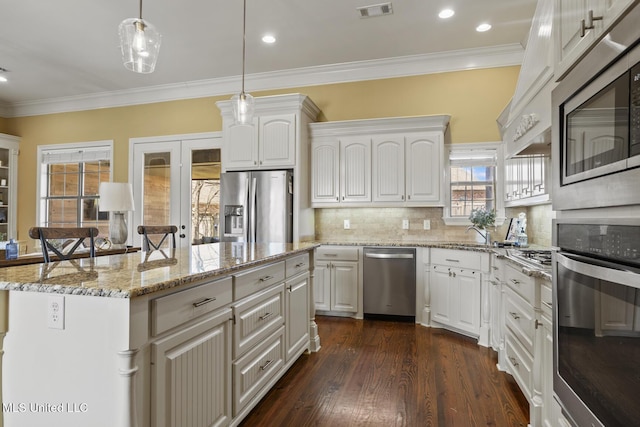 kitchen featuring visible vents, a kitchen island, decorative backsplash, dark wood-style floors, and stainless steel appliances