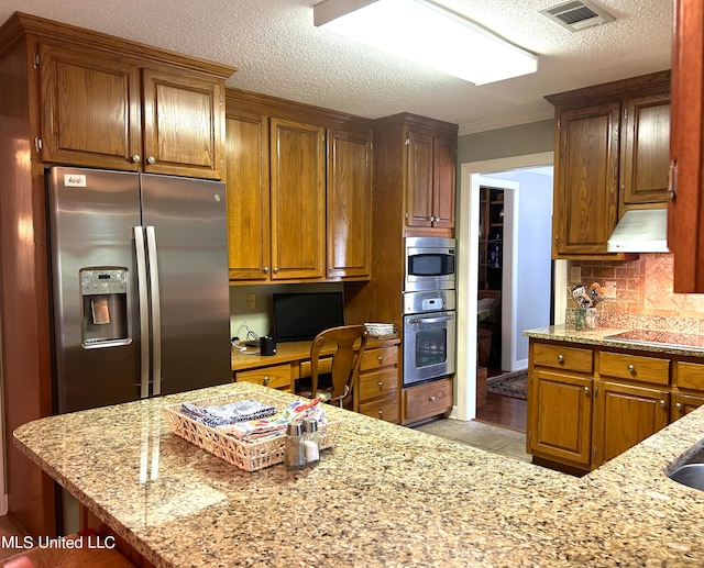 kitchen with decorative backsplash, built in desk, stainless steel appliances, ventilation hood, and light stone countertops