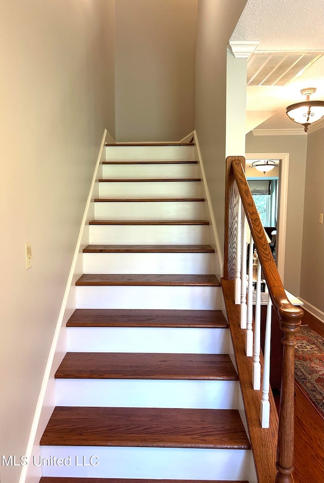 staircase with ornamental molding and hardwood / wood-style flooring