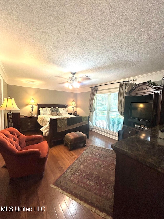 bedroom featuring ceiling fan, wood-type flooring, a textured ceiling, and ornamental molding