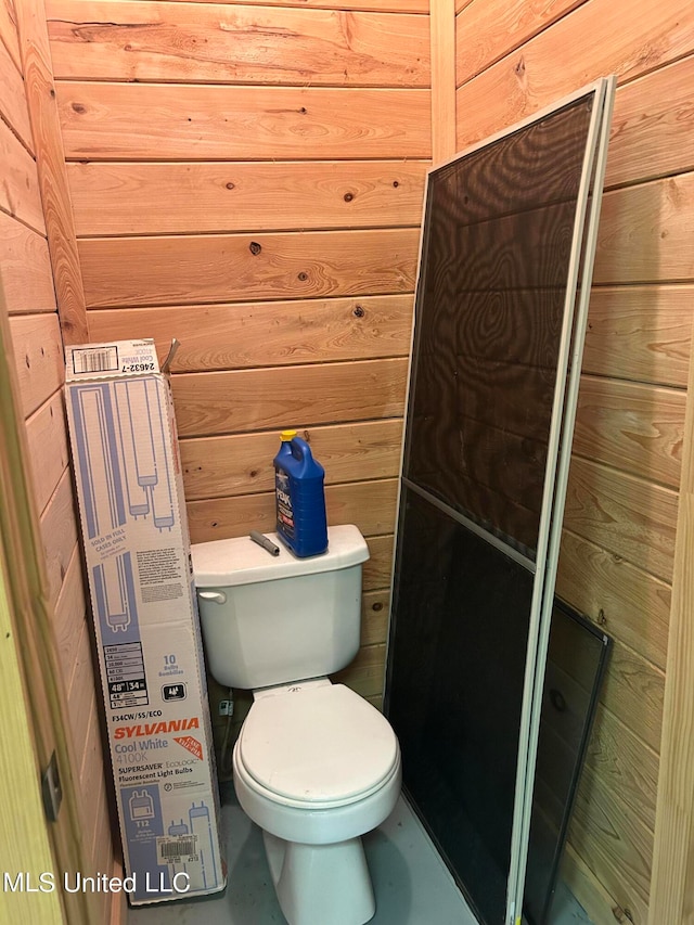 bathroom featuring toilet and wood walls