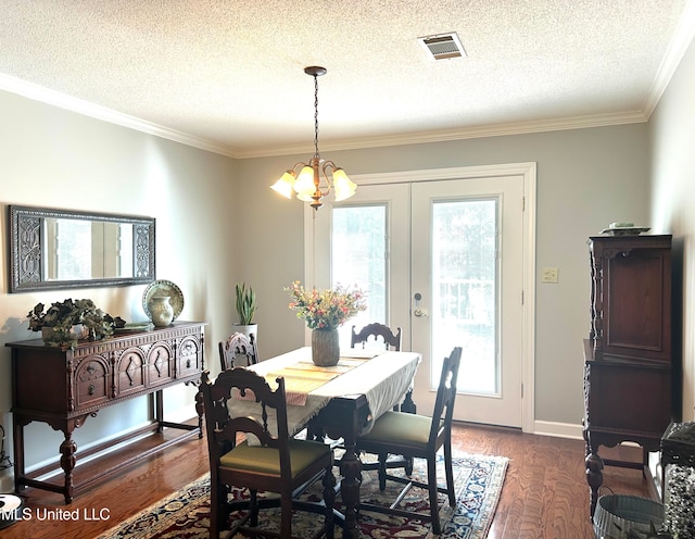 dining area featuring an inviting chandelier, a textured ceiling, crown molding, dark wood-type flooring, and french doors