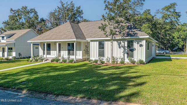 view of front of home featuring board and batten siding, a front lawn, covered porch, and roof with shingles