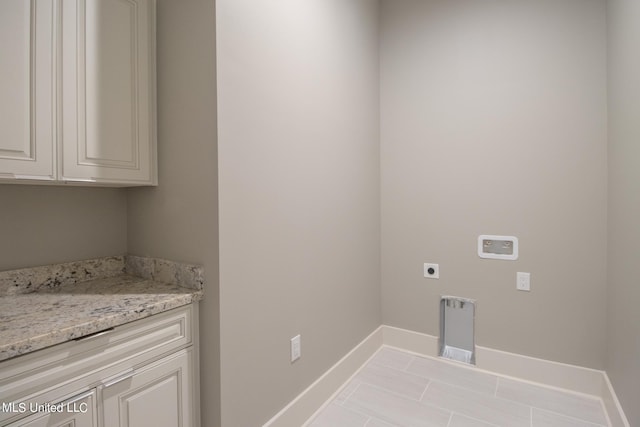 laundry area with light tile patterned flooring, electric dryer hookup, and cabinets