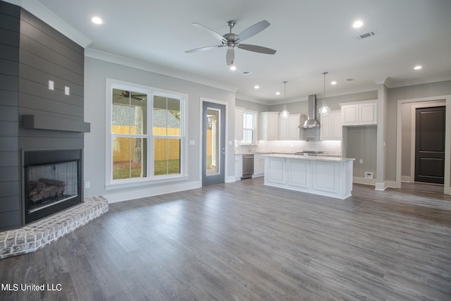 unfurnished living room featuring crown molding, ceiling fan, a fireplace, and hardwood / wood-style flooring