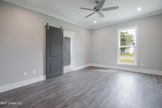 spare room featuring ceiling fan, dark hardwood / wood-style floors, crown molding, and a barn door