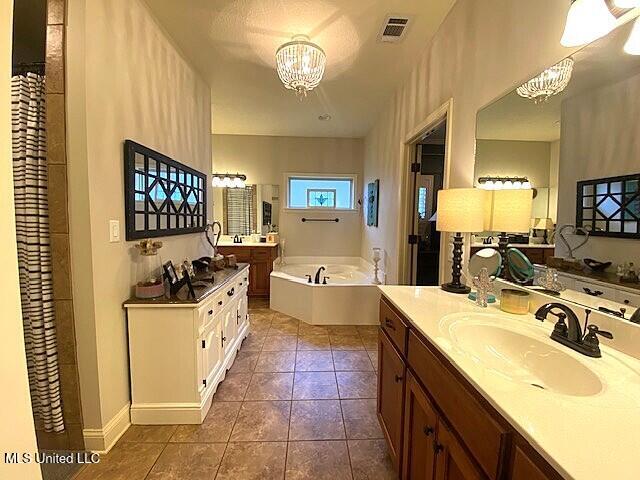 771 Robertson Way, Hernando, MS 38632 - bathroom with a chandelier, two vanities, a garden tub, and tile patterned flooring