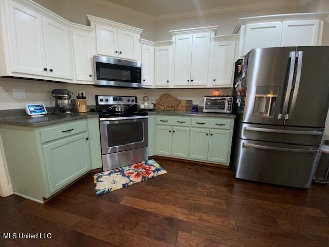 771 Robertson Way, Hernando, MS 38632 - kitchen featuring appliances with stainless steel finishes, dark wood-style floors, ornamental molding, white cabinets, and dark countertops