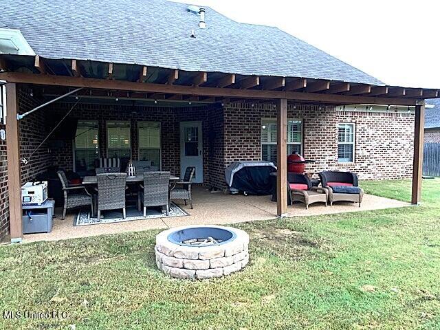 771 Robertson Way, Hernando, MS 38632 - back of property with an outdoor living space with a fire pit, a yard, a patio area, and a shingled roof